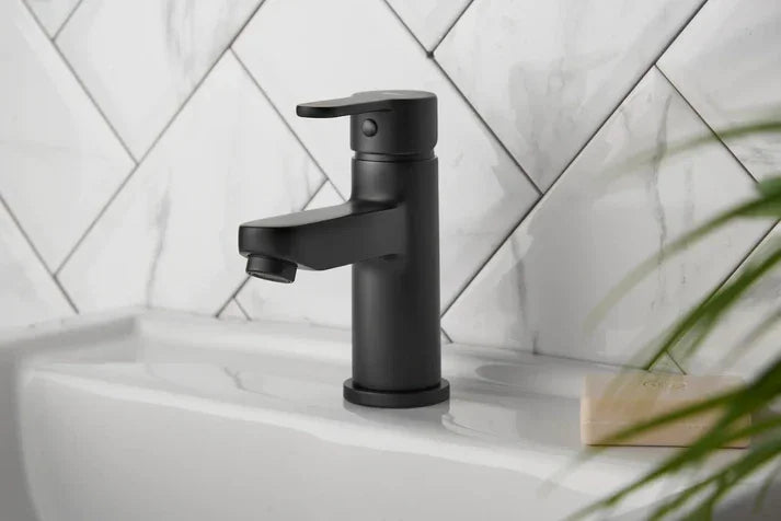 Matt black cloakroom basin mixer tap installed on white sink with marble tiles, luxury bathroom