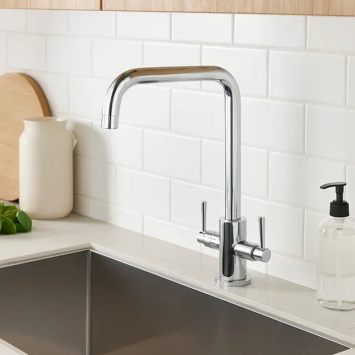 Modern chrome kitchen sink mixer tap with dual handles, set against white subway tiles